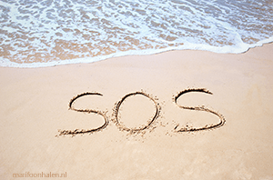 SOS sein (Save Our Souls) gemarkeerd op het strand.